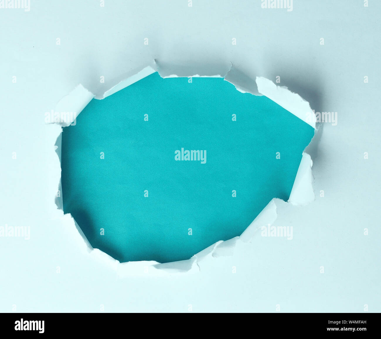 A torn hole in the paper on a blue background for your advertising text Stock Photo