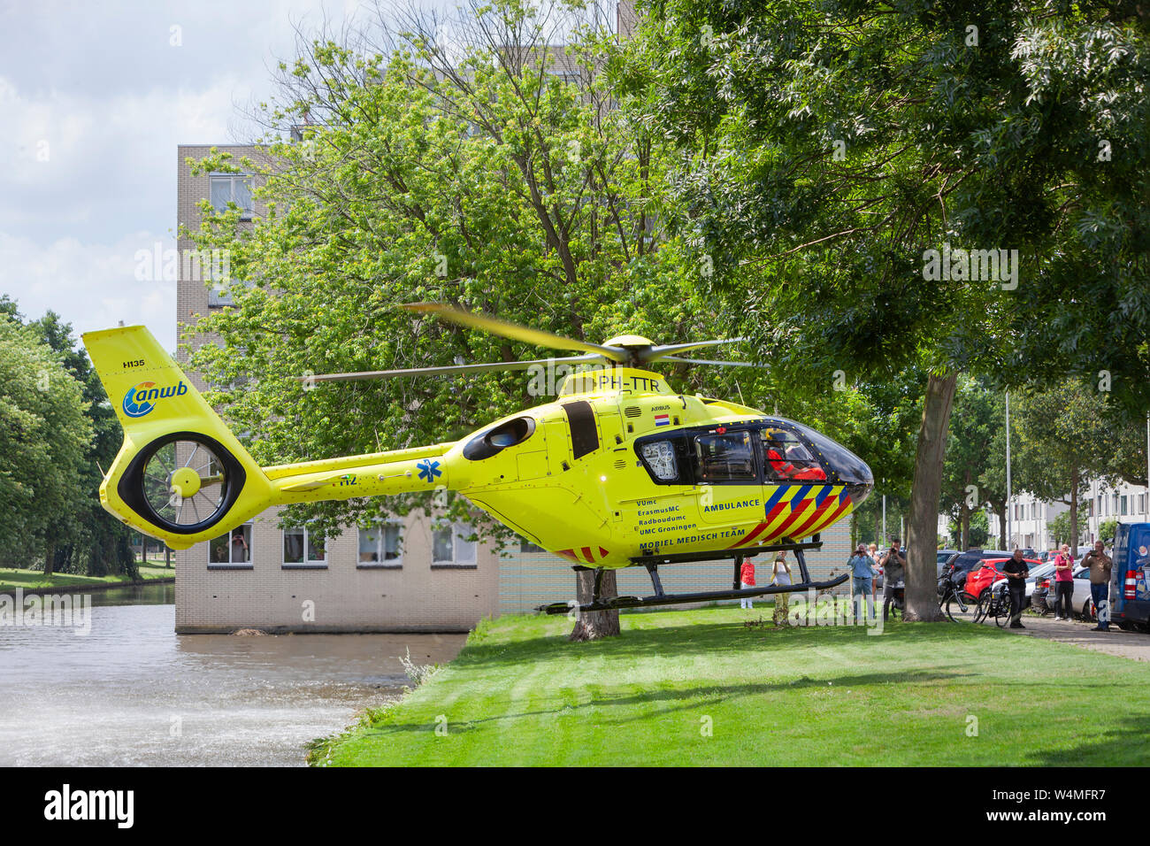 Rotterdam, Netherlands – June 22, 2019: Trauma helicopter landing near trees and water in residential district Prinsenland in Rotterdam for a medical Stock Photo