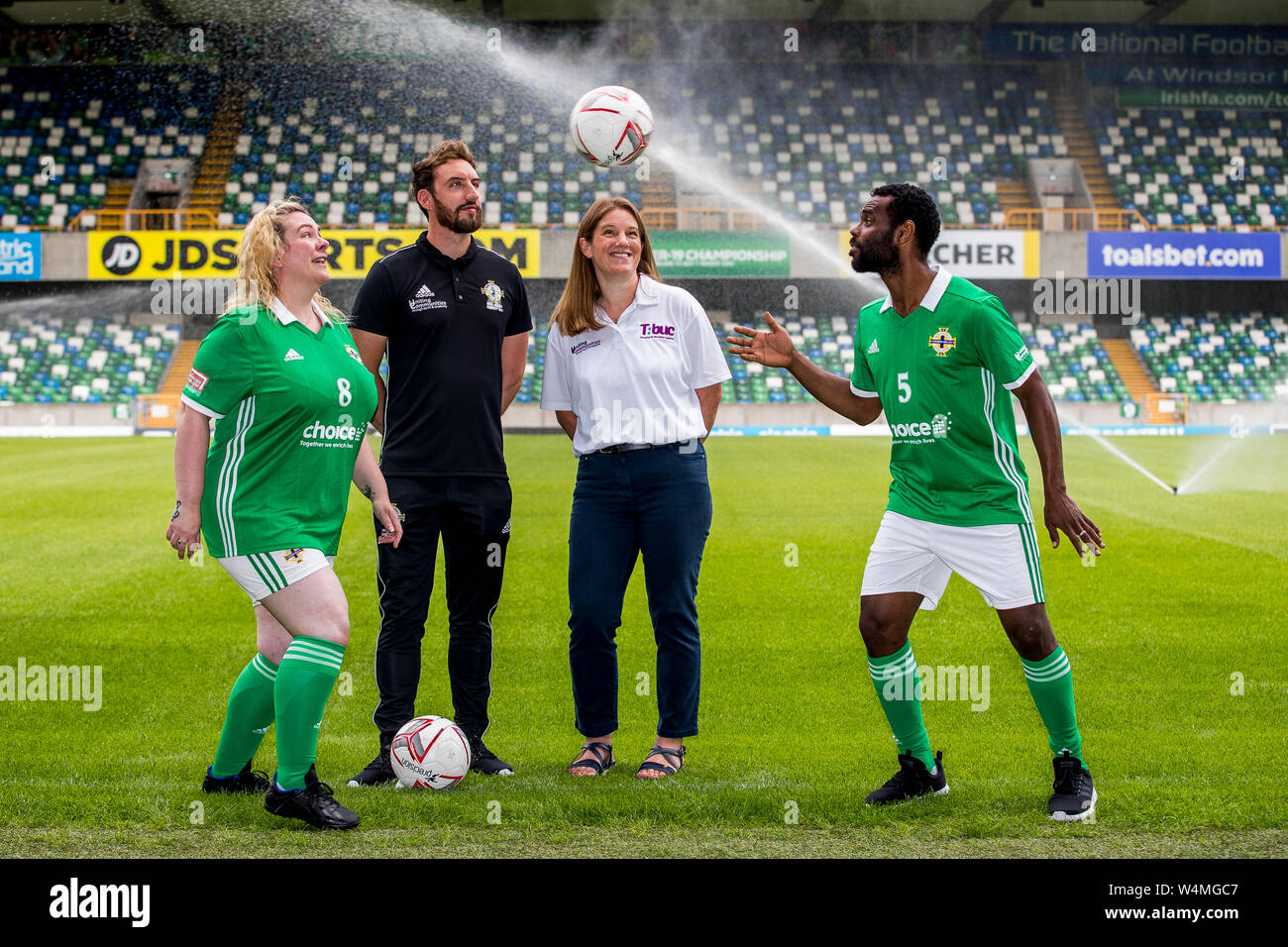 Ahemd Elneel (right), captain of the Northern Ireland homeless football team, and who is originally from Sudan heads the ball to Northern Ireland's homeless woman's player, Janette Kelly (left), as Justin McMinn (second from left) of Street Soccer NI, and Katherine Hill (second from right), Director of Active Communities at the Department for Communities watch on, during a photocall at The National Stadium, Windsor Park, ahead of the teams departure tomorrow for the Homeless World Cup in Cardiff this coming weekend. Stock Photo