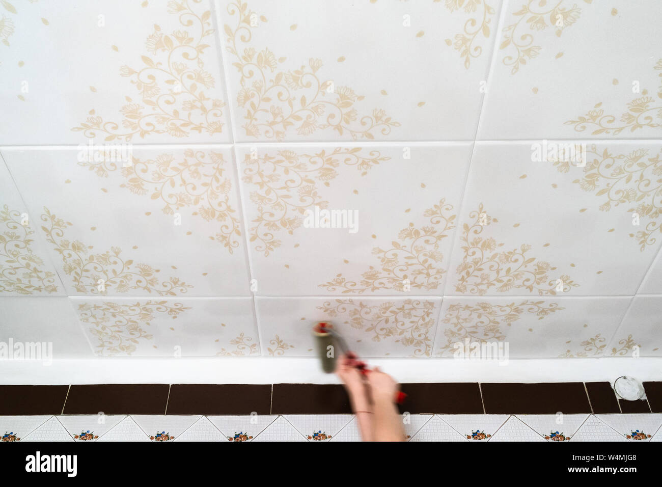 Fixing Styrofoam Ceiling Tiles With Roller At Home Kitchen Stock