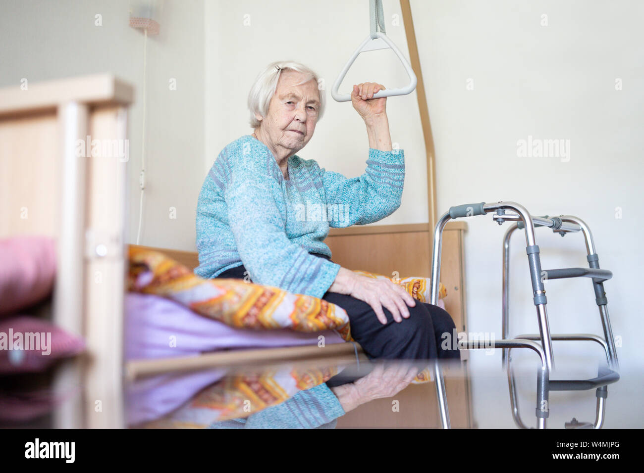 Elderly 96 years old woman sitting on medical bed in hospic. Stock Photo