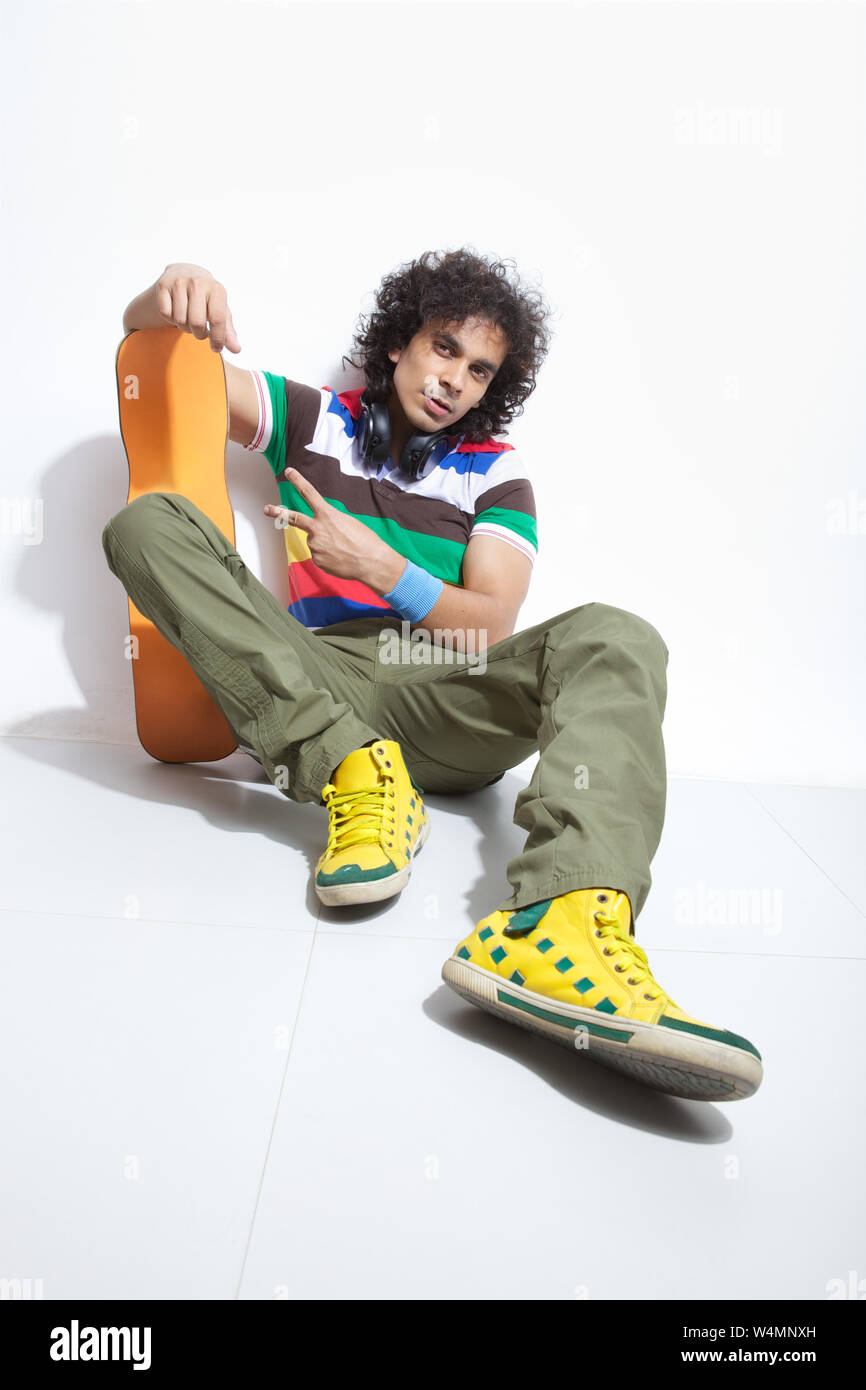 Man holding skateboard and showing peace sign Stock Photo