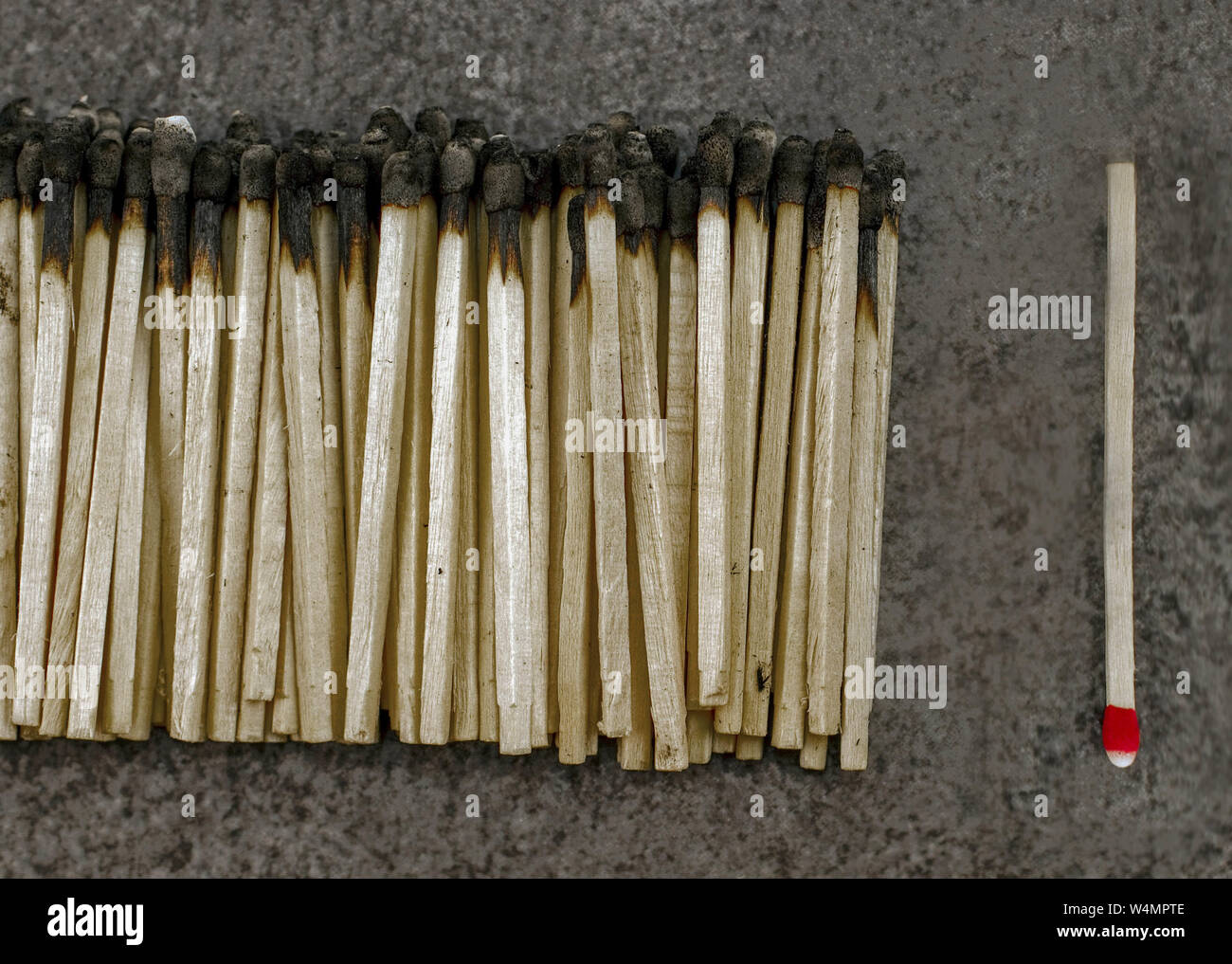 A single unused match next to a bunch of burnt ones. Stock Photo