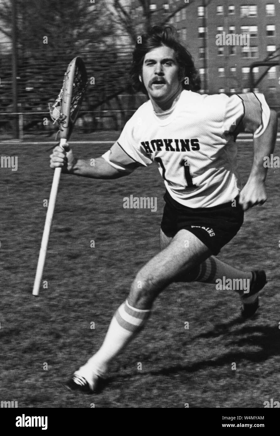 Johns Hopkins lacrosse player Bill Nolan, running with his stick in his right hand, wearing shorts and a Hopkins jersey, with a serious facial expression, 1970. From the Historical Photographs Collection. () Stock Photo