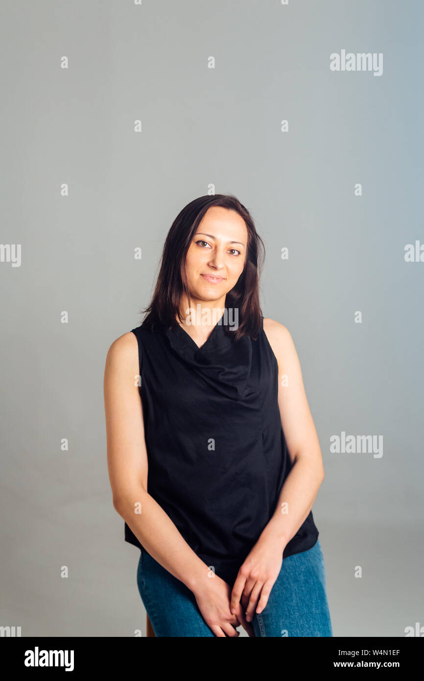Studio portrait of a woman in a black dress against a plain grey ...