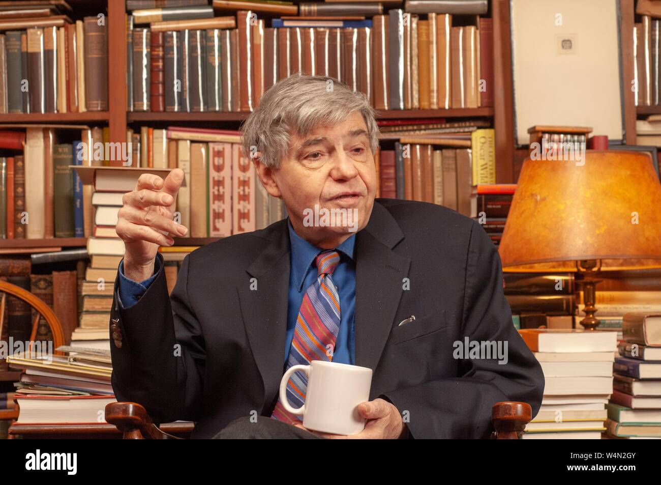 Close-up of Richard A Macksey, Professor of Humanities, speaking while seated and holding a cup, likely in the private library he bequeathed to the Johns Hopkins University, December 14, 2006. From the Homewood Photography Collection. () Stock Photo