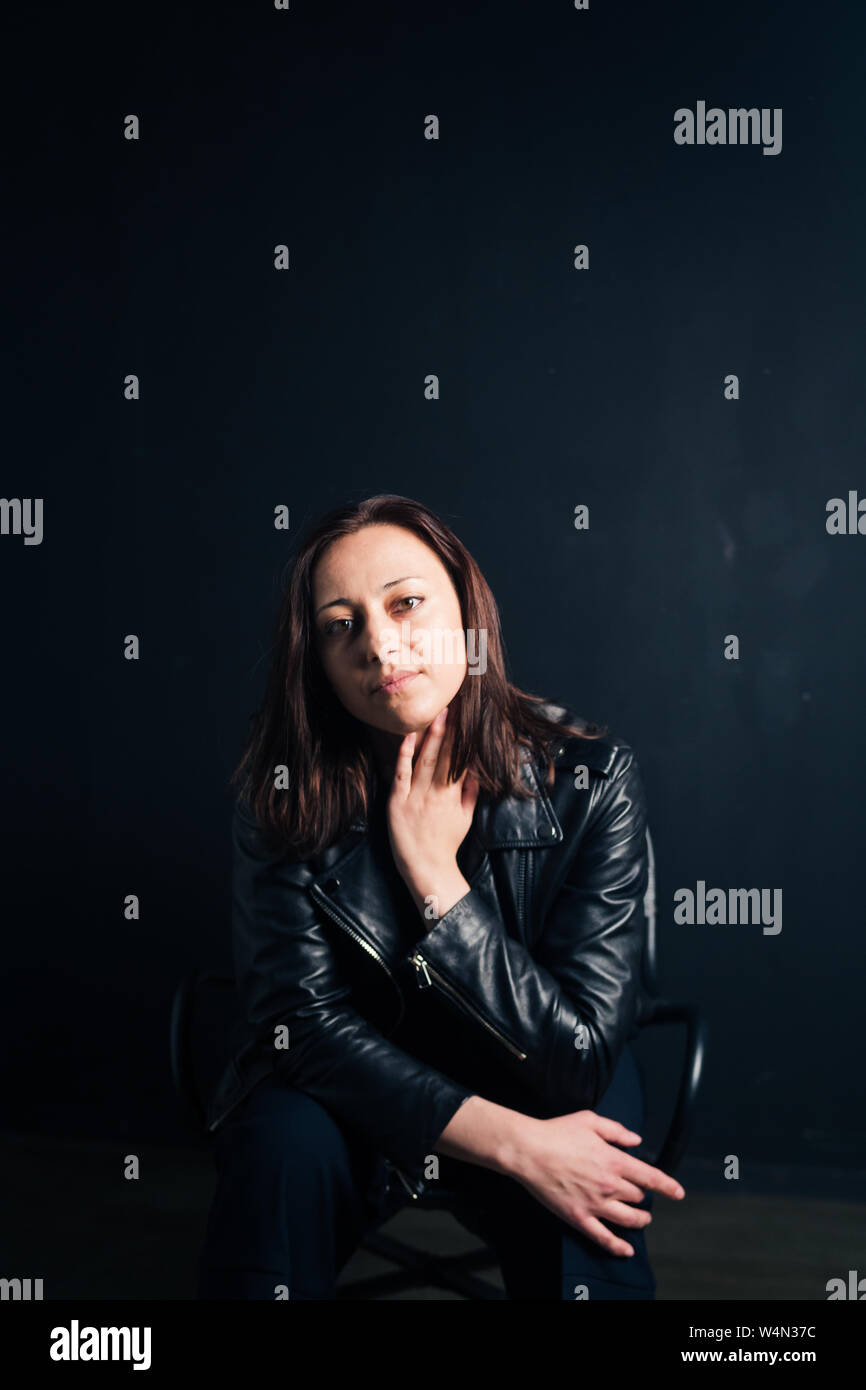 Studio portrait of an attractive young woman in a black leather jacket ...