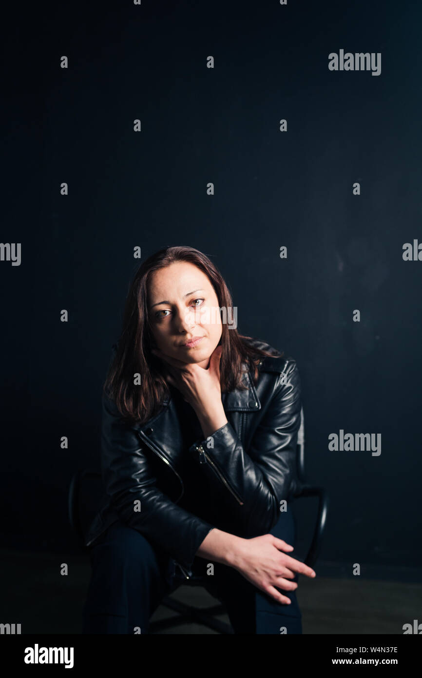 Studio portrait of an attractive young woman in a black leather jacket ...