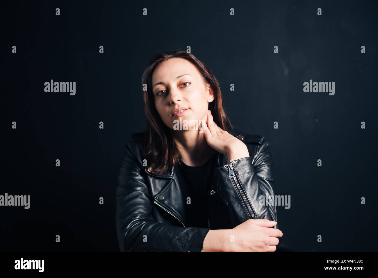 Studio portrait of an attractive young woman in a black leather jacket ...