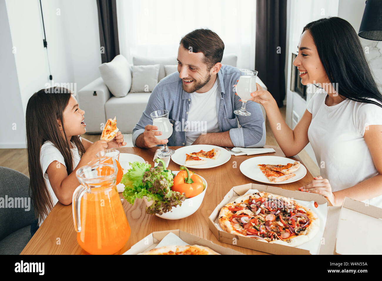 happy multi ethnic family, mother, father and daughter during dinner.Eating delicious pizza with family Stock Photo