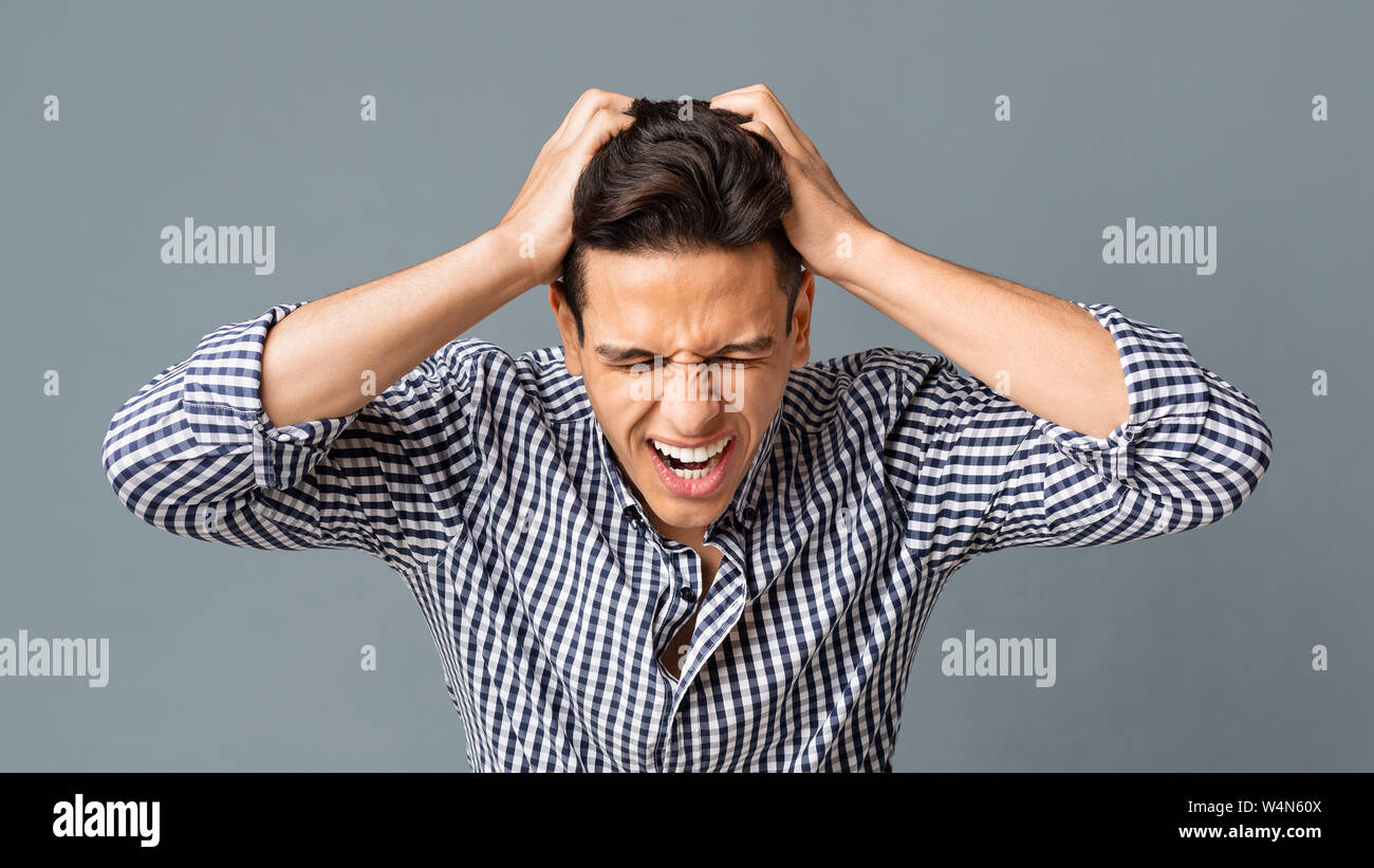 Frustrated Young Man Pulling His Hair Out On Gray Background Stock Photo Alamy