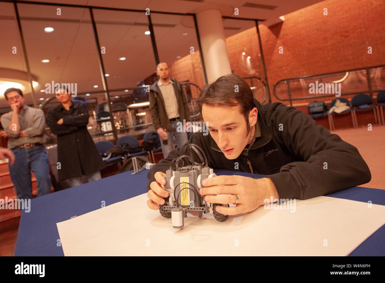A competitor leans over a table to adjust his project during a Lego Robotics Competition associated with Engineering Programs for Professionals (EPP) at the Johns Hopkins University, Baltimore, Maryland, December 3, 2007. From the Homewood Photography Collection. () Stock Photo