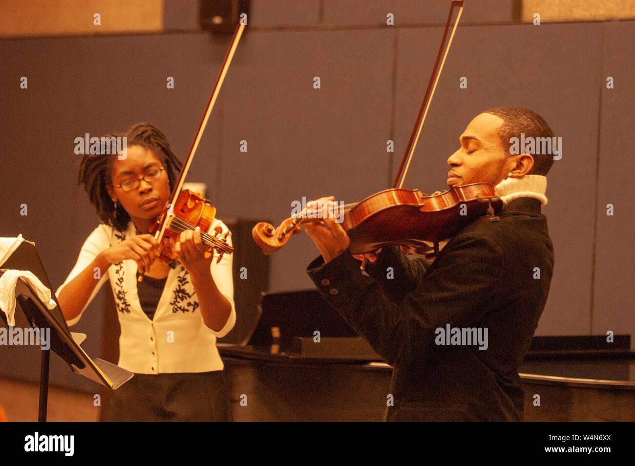 Medium shot of a pair of musicians playing violins, at an event associated with Black History Month at the Johns Hopkins University, Baltimore, Maryland, February 26, 2006. From the Homewood Photography Collection. () Stock Photo