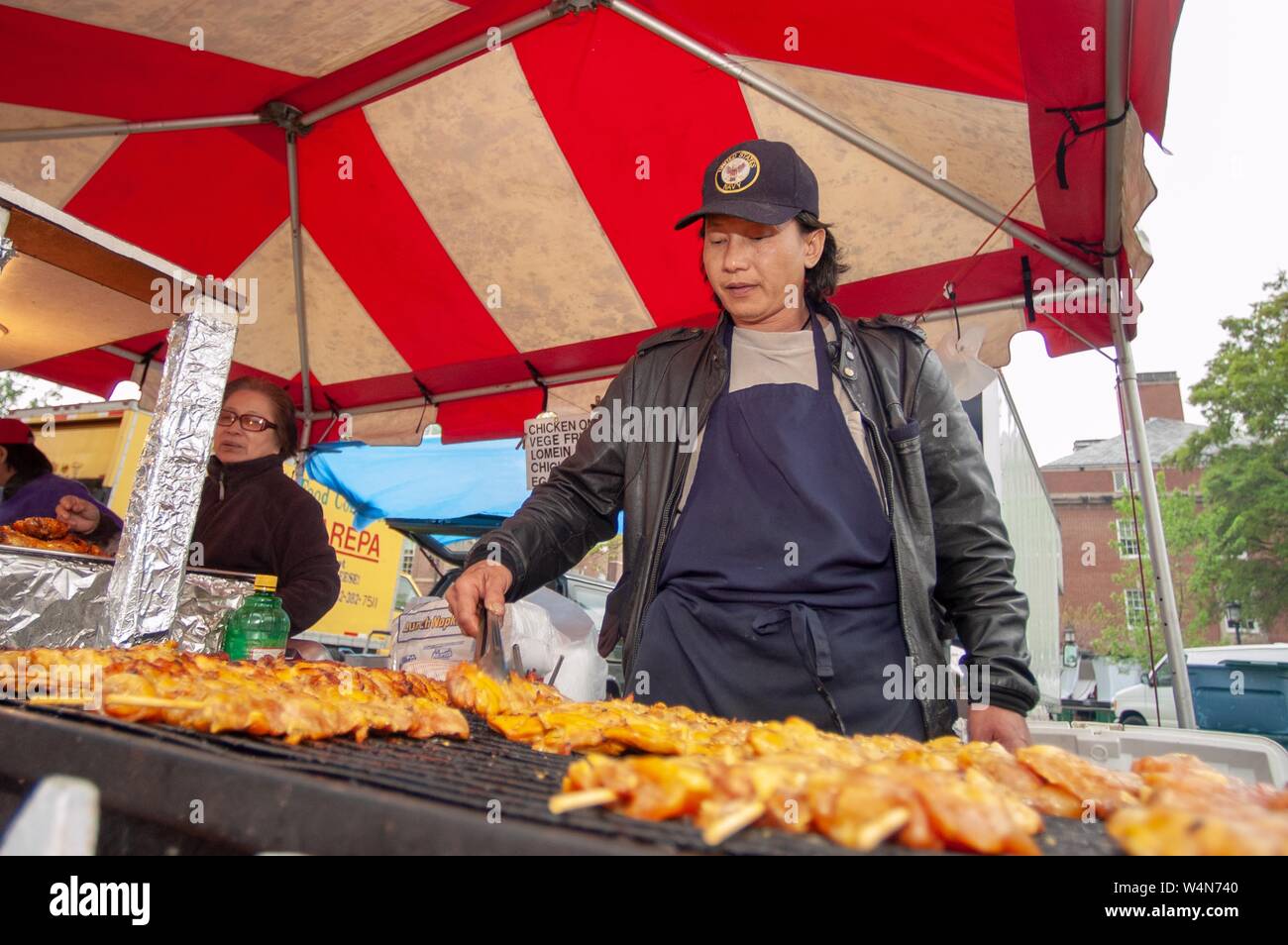 A vendor cooks chicken on a large outdoor grill during the Spring Fair carnival at the Homewood Campus of the Johns Hopkins University in Baltimore, Maryland, April 22, 2006. From the Homewood Photography collection. () Stock Photo
