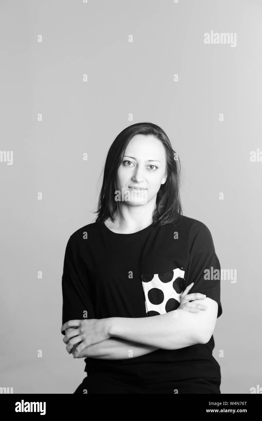 Black and white studio portrait of an attractive woman in a black t-shirt against plain background Stock Photo