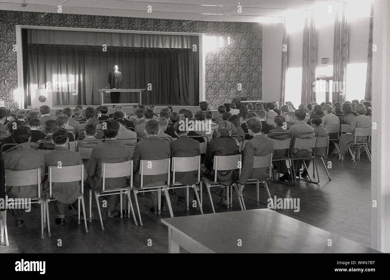 1950s, historical, headmaster in robe, on a stage in the school hall addressing his pupils, England, UK. Stock Photo