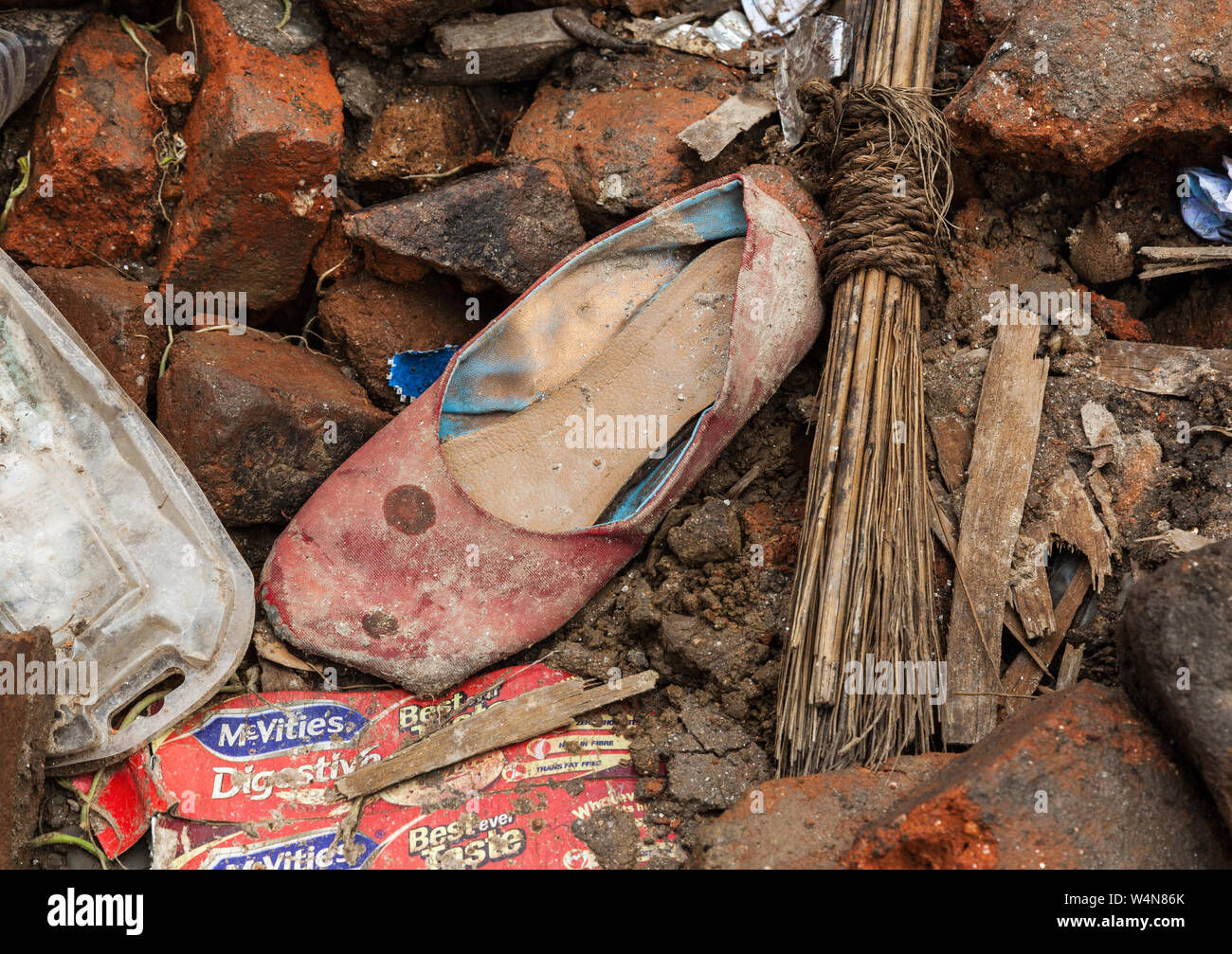 A dirty red slip-on shoe amongst rubble after an earthquake in Kathmandu Stock Photo
