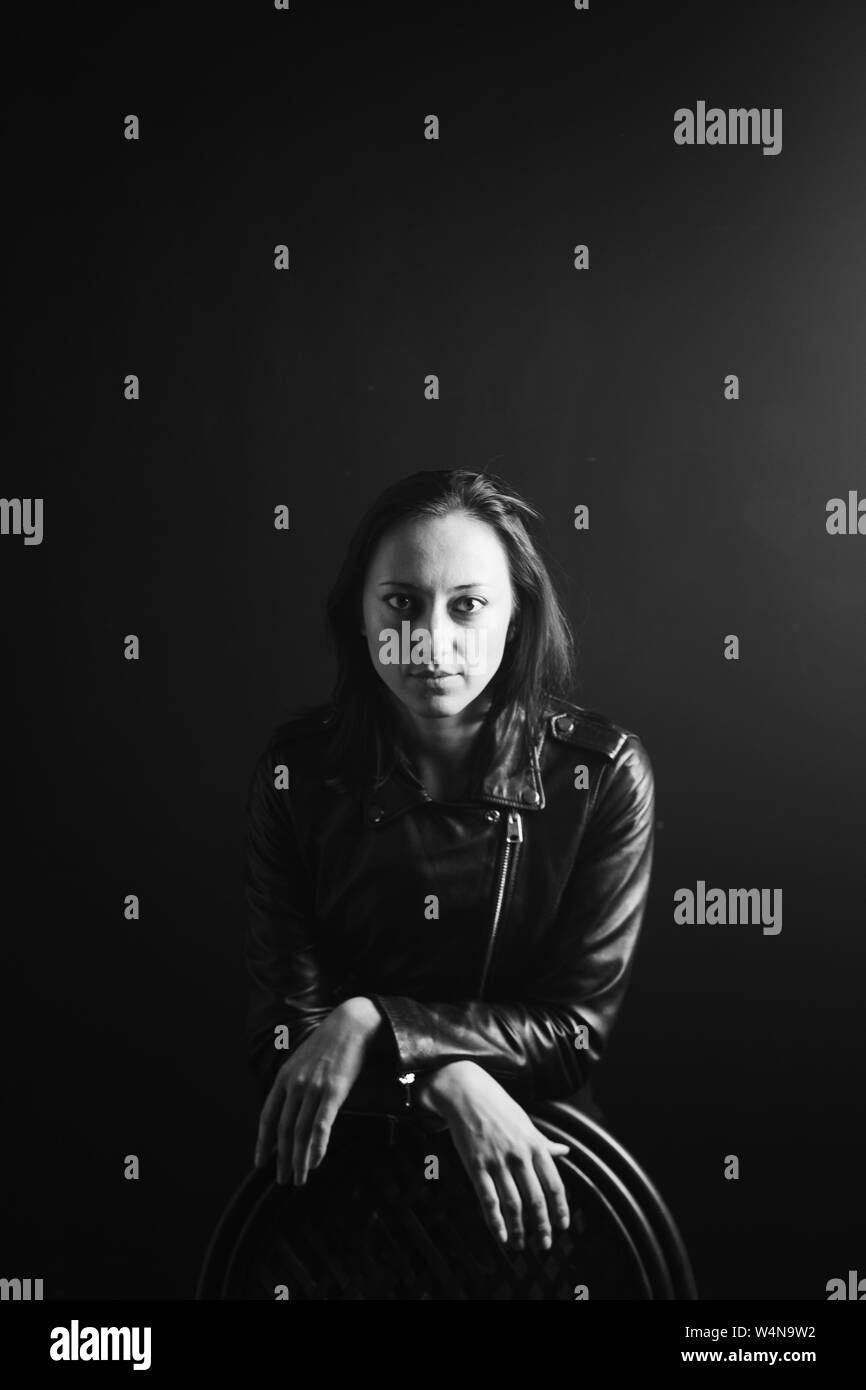 Studio portrait of an attractive young woman in a black leather jacket ...
