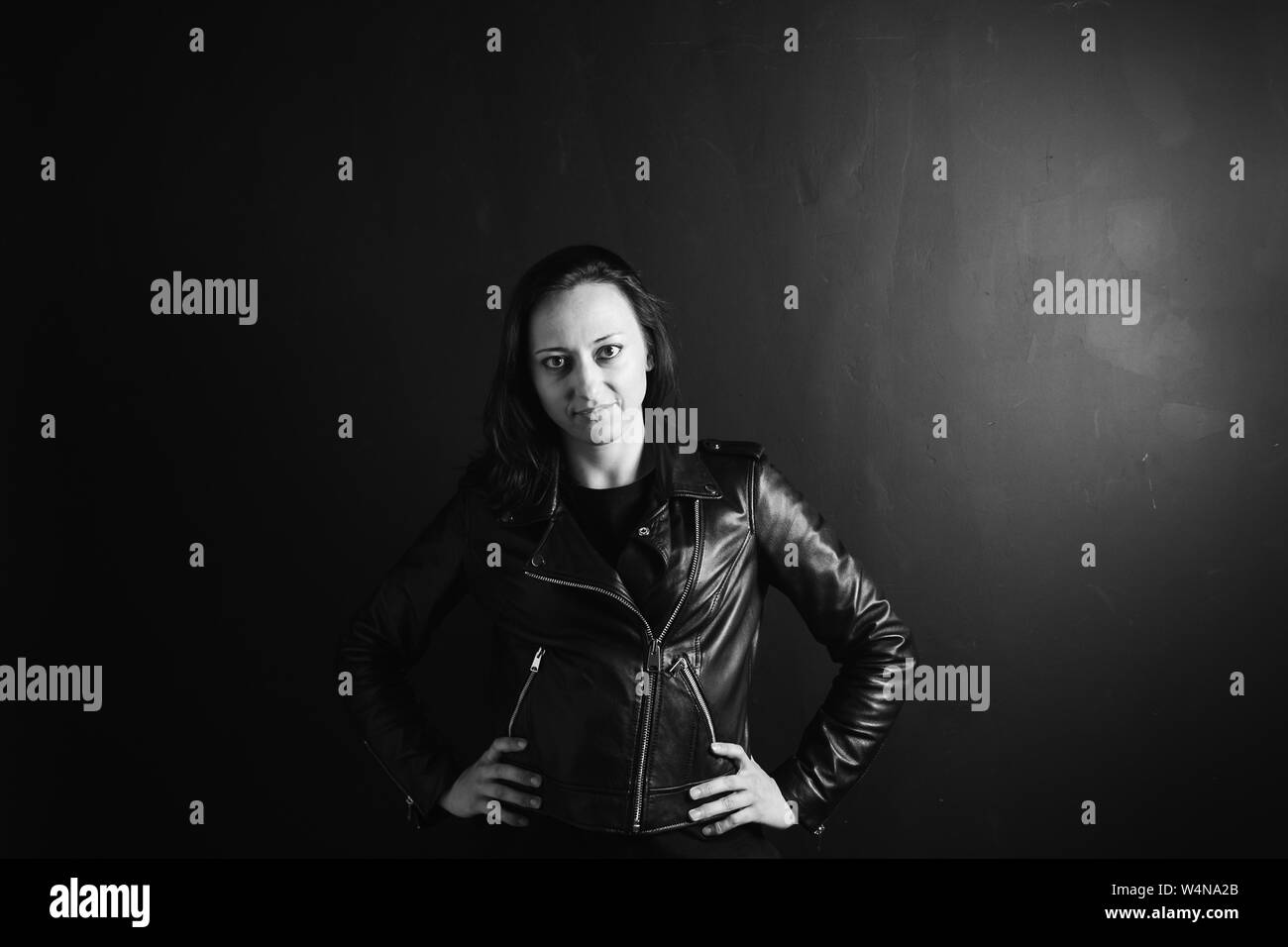Studio portrait of an attractive young woman in a black leather jacket ...