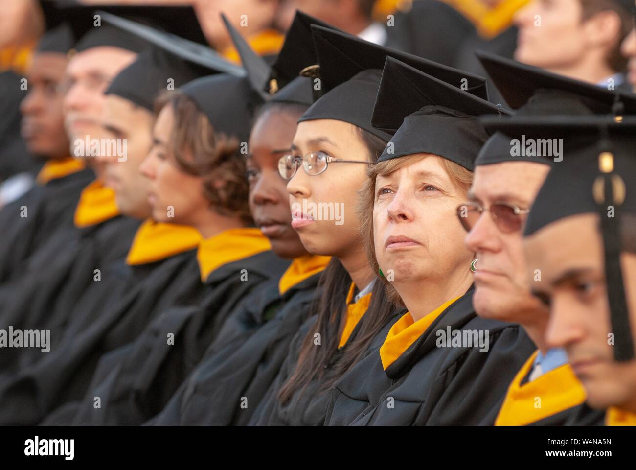 Engineering graduands, wearing caps and gowns, sit in a row during a