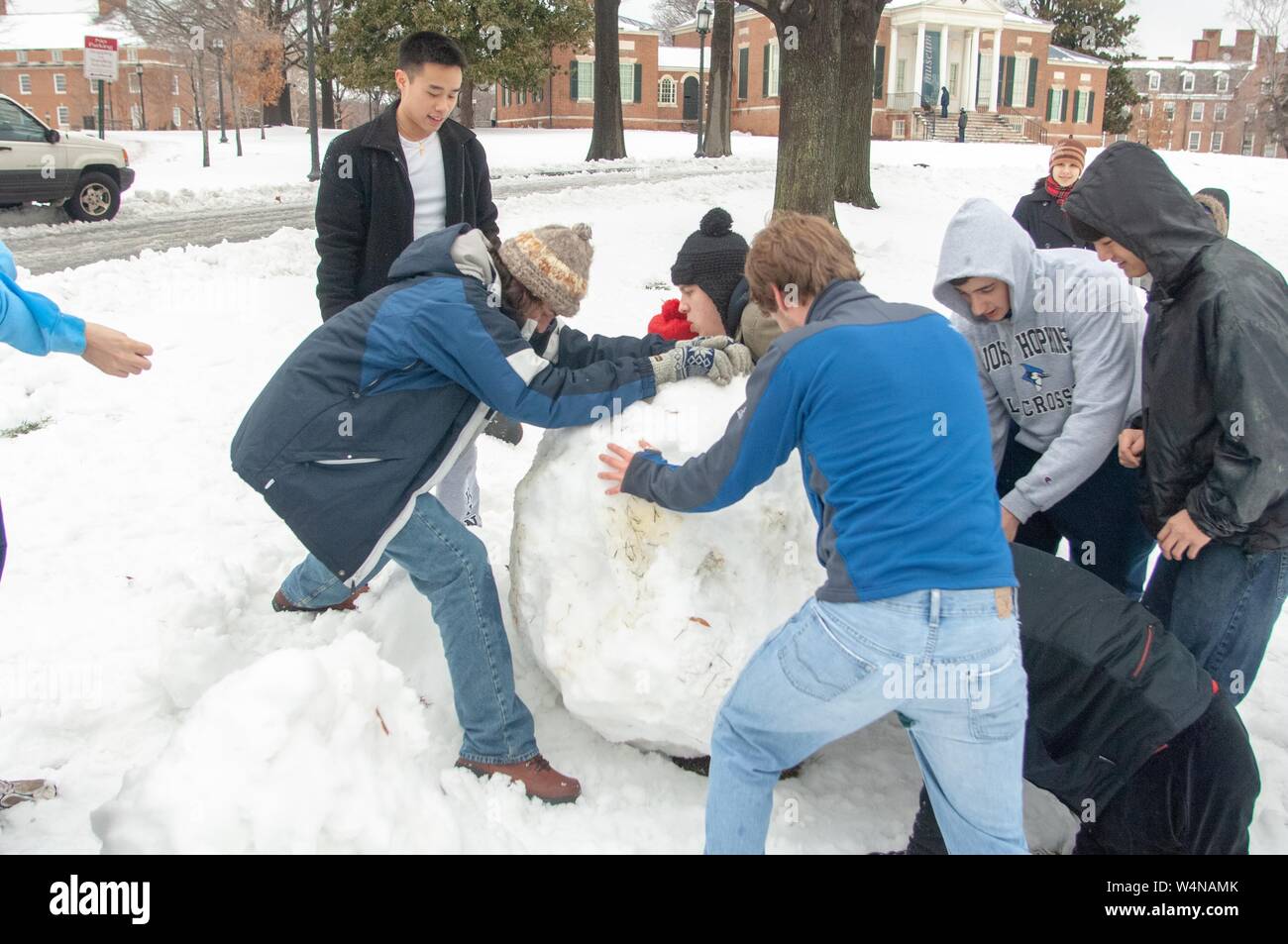 A group of students works together to roll a giant snowball, on a quad near the Homewood Museum, at the Johns Hopkins University, Baltimore, Maryland, February 14, 2007. From the Homewood Photography Collection. () Stock Photo