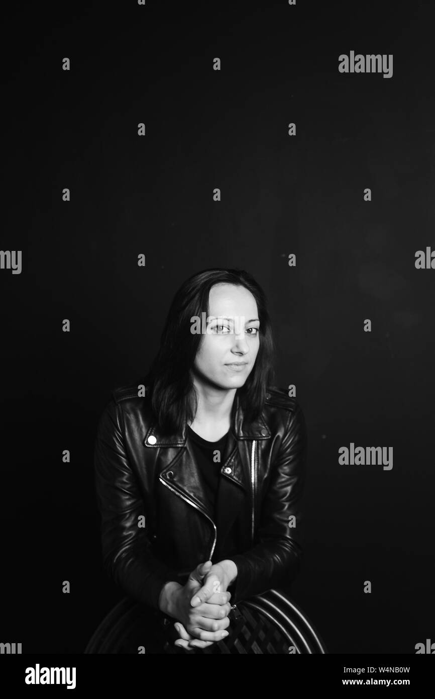 Studio portrait of an attractive young woman in a black leather jacket ...