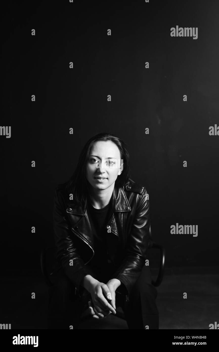 Studio portrait of an attractive young woman in a black leather jacket ...