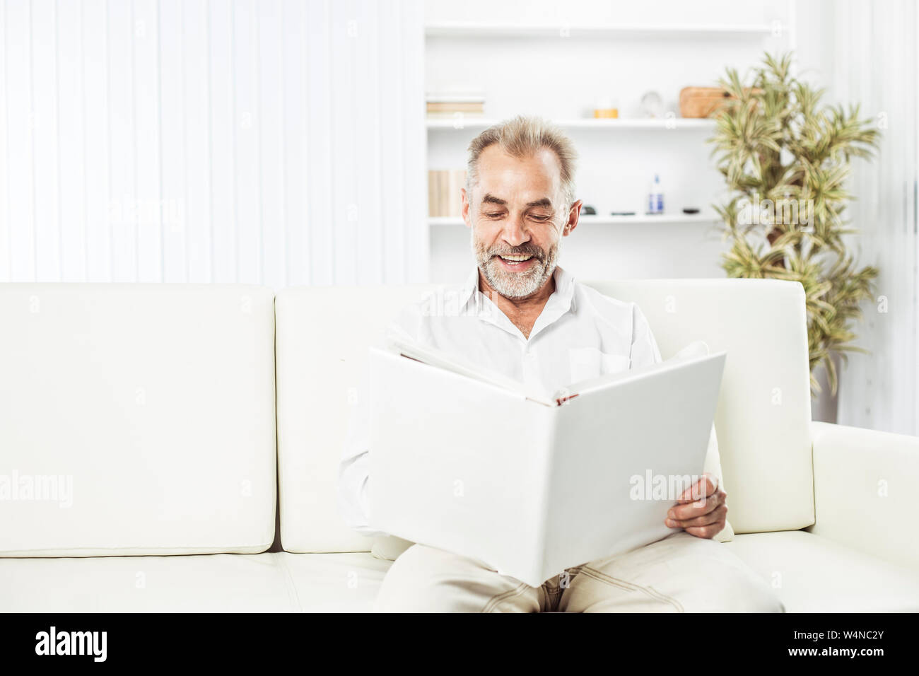 businessman with a magazine sitting on sofa in bright office. the photo has a empty space for your text Stock Photo