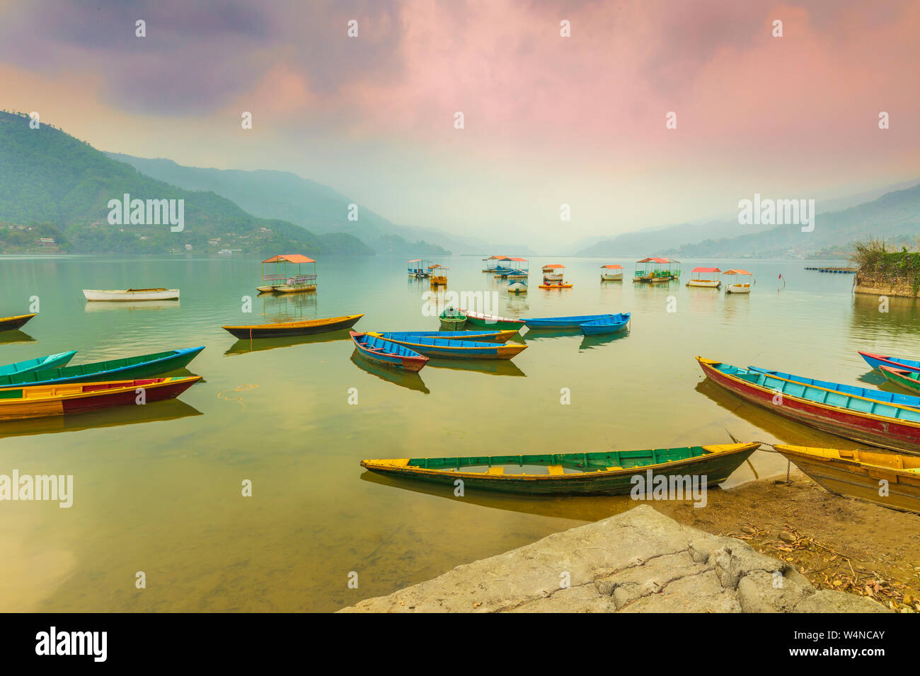 Colorful boats parked in Phewa lake waiting for tourists and background on sunset view from Pokhara lake Nepal. Stock Photo