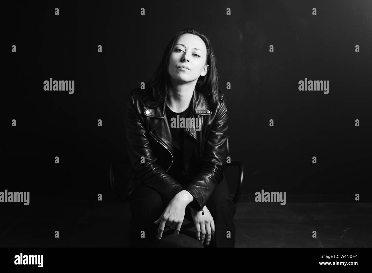 Studio portrait of an attractive young woman in a black leather jacket ...