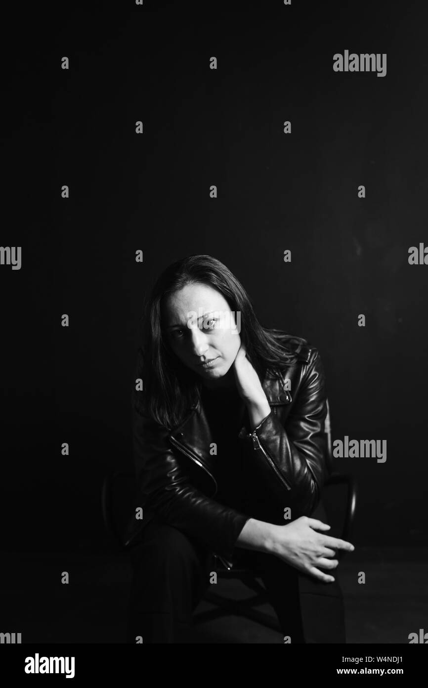 Studio portrait of an attractive young woman in a black leather jacket ...