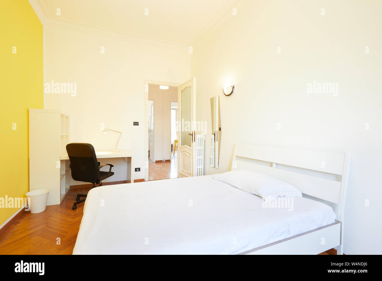 Bedroom interior in renovated apartment with parquet floor and yellow wall Stock Photo