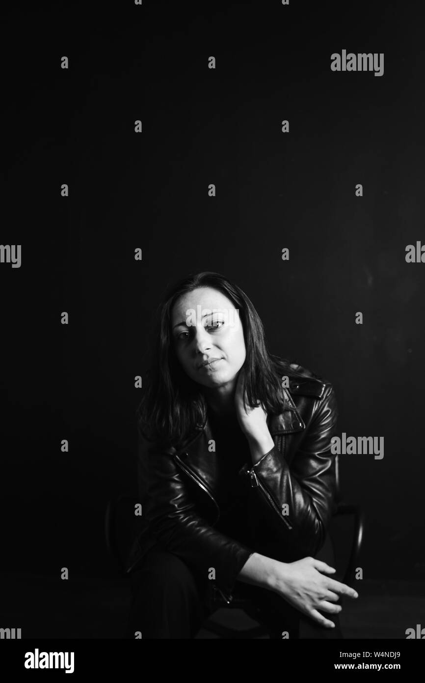 Studio portrait of an attractive young woman in a black leather jacket ...