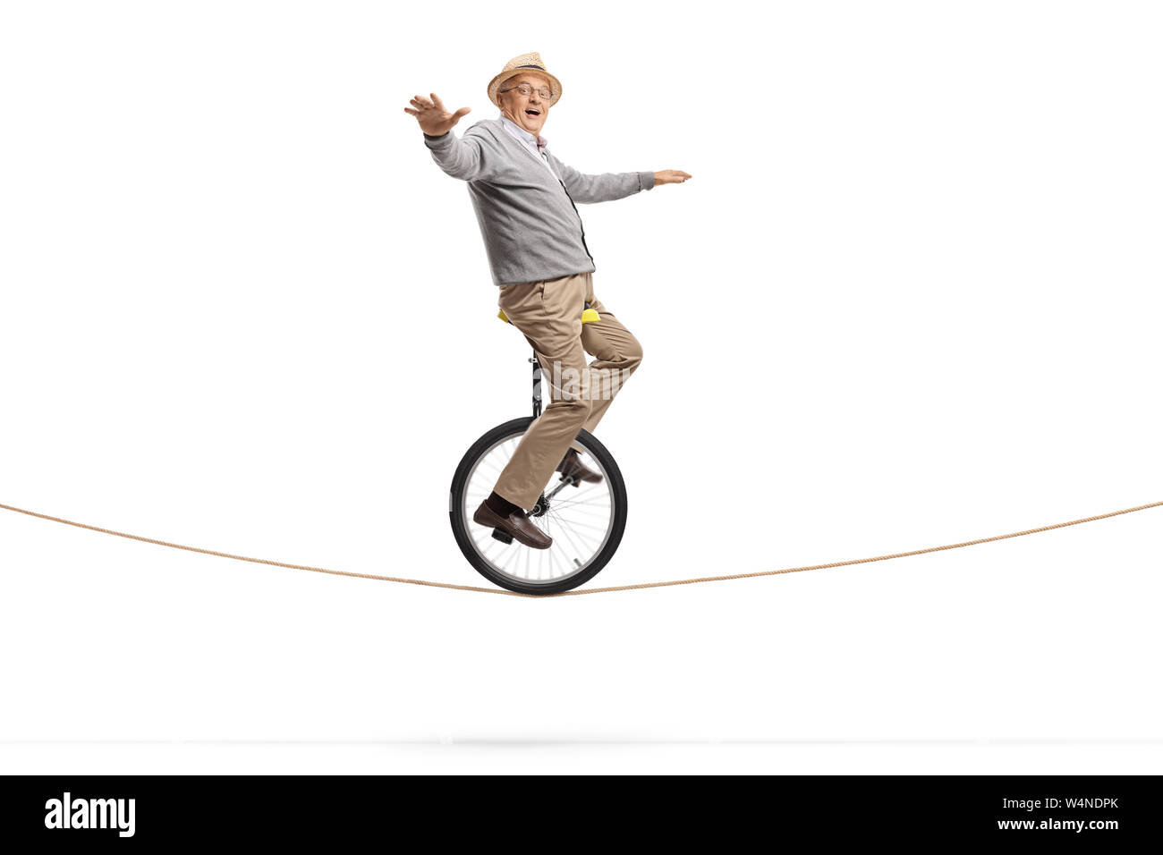 Full length shot of an elderly man riding a unicycle on a rope and balancing with hands isolated
