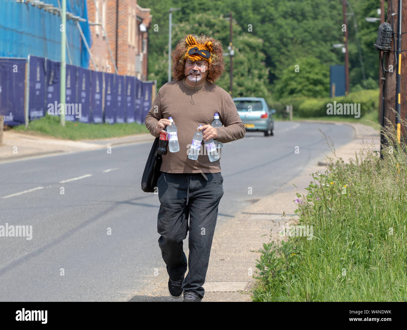Man in a fancy tiger headdress carrying bottled drinks Stock Photo