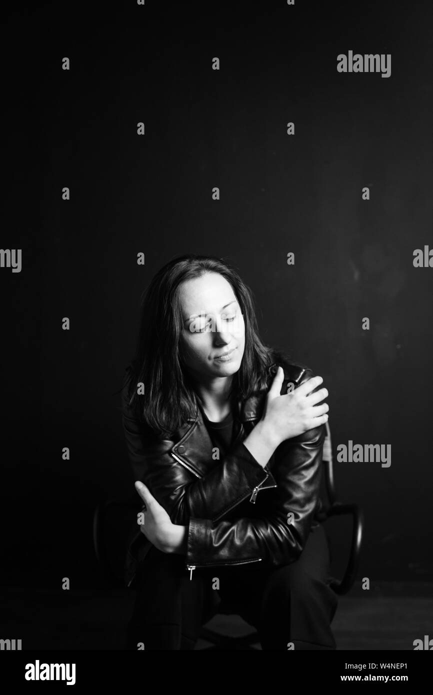 Studio portrait of an attractive young woman in a black leather jacket ...