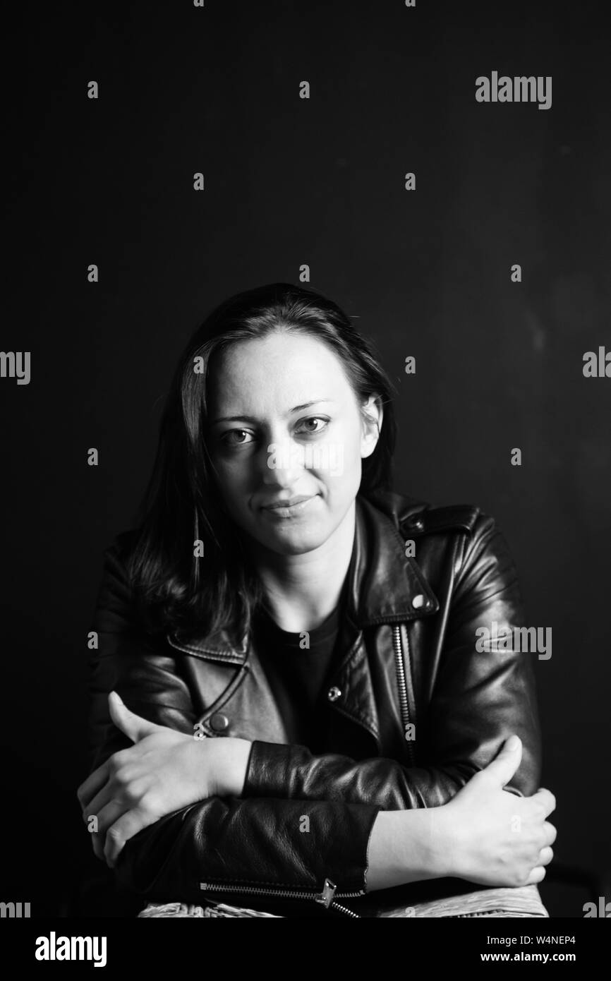 Studio portrait of an attractive young woman in a black leather jacket ...