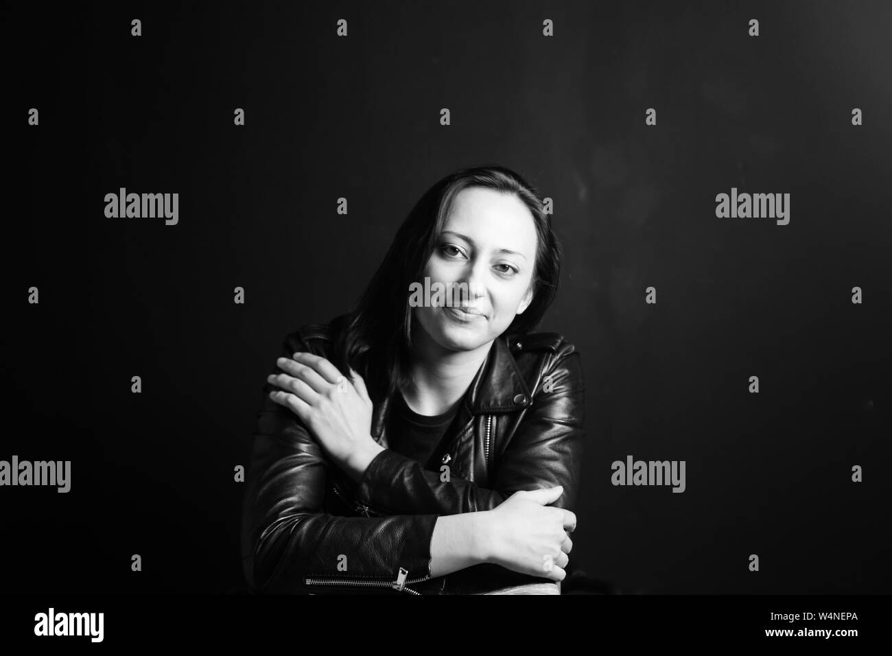 Studio portrait of an attractive young woman in a black leather jacket ...