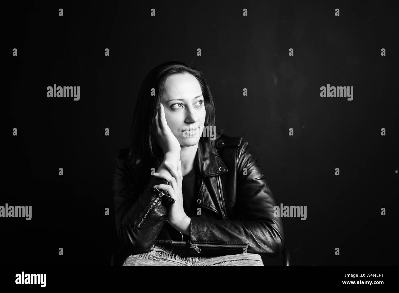 Studio portrait of an attractive young woman in a black leather jacket ...