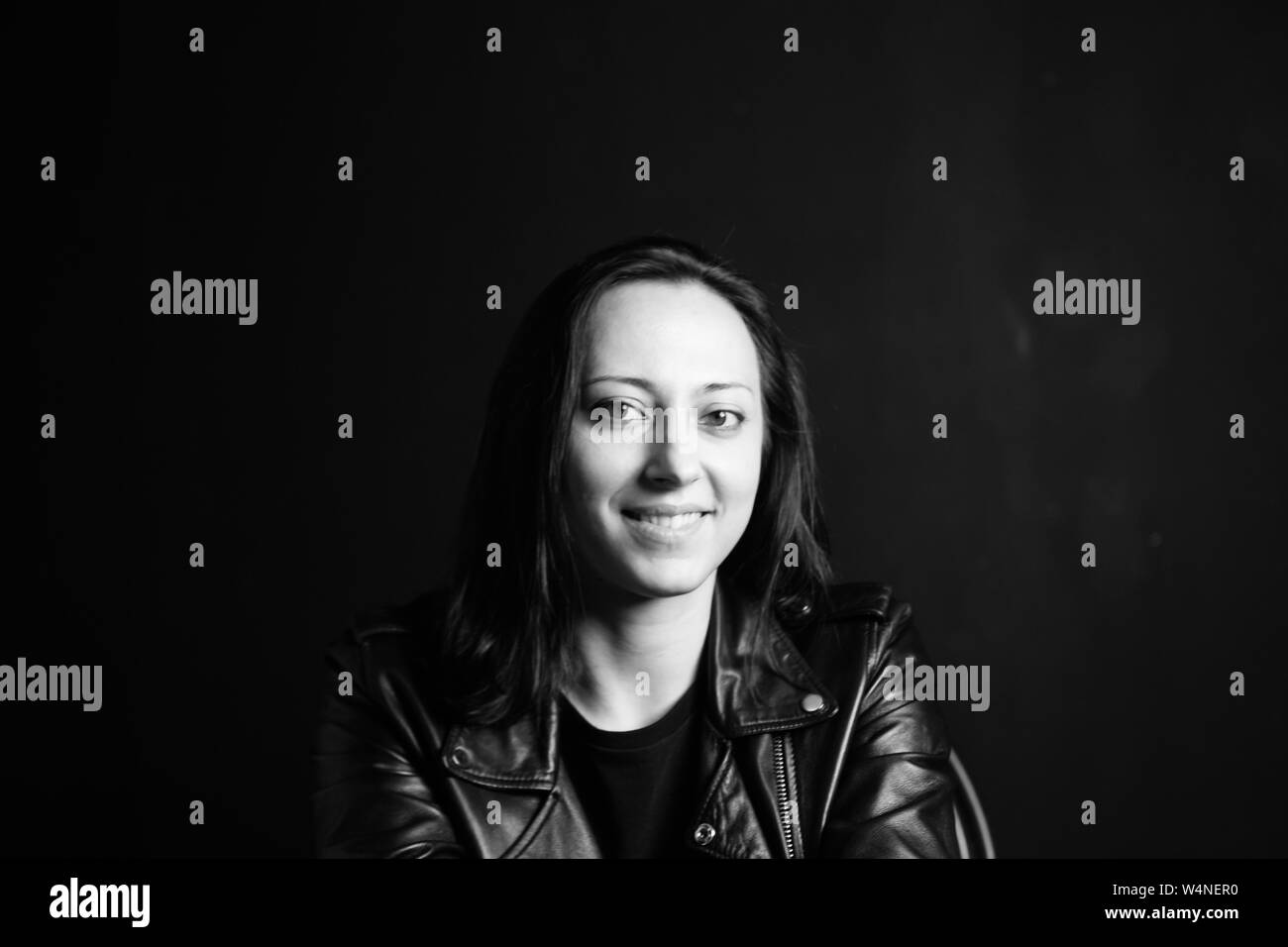 Studio portrait of an attractive young woman in a black leather jacket ...