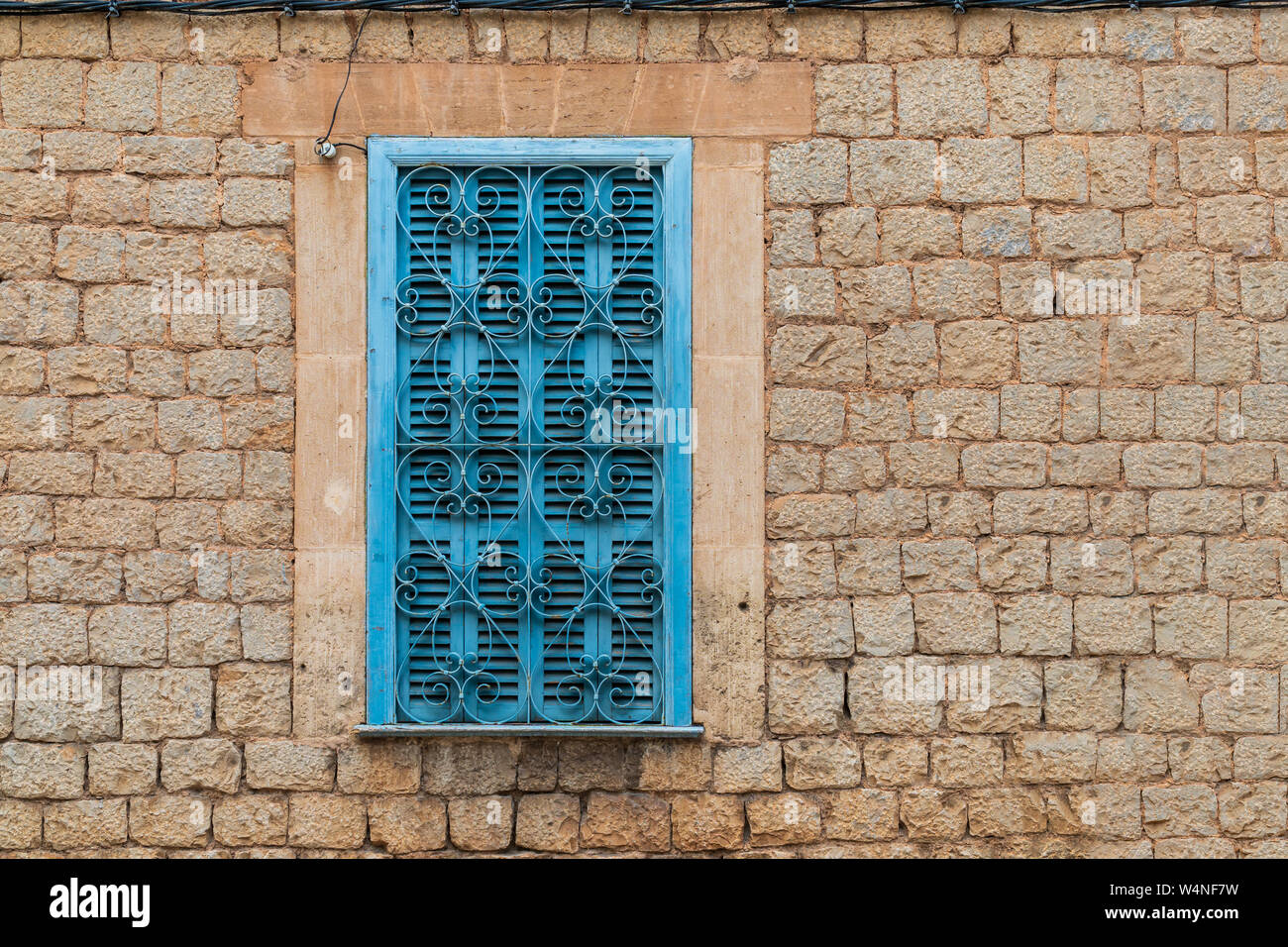 Turquoise window shutters with heart-shaped window grating in a brick wall facade in Valldemossa, Majorca, Spain - head-on view, landscape format, cop Stock Photo