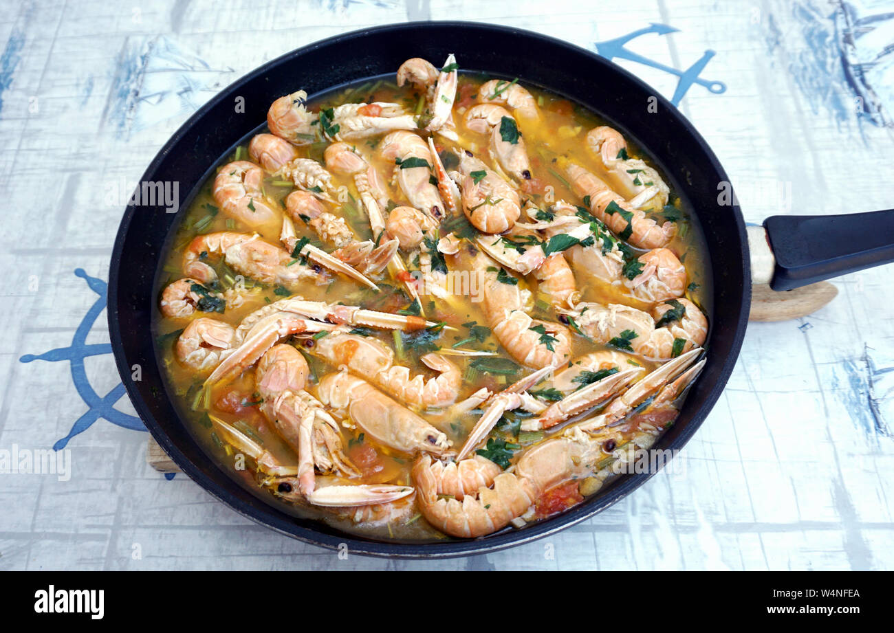 Small shrimps Nephrops norvegicus prepared like stew in the skillet on the table, flat lay Stock Photo