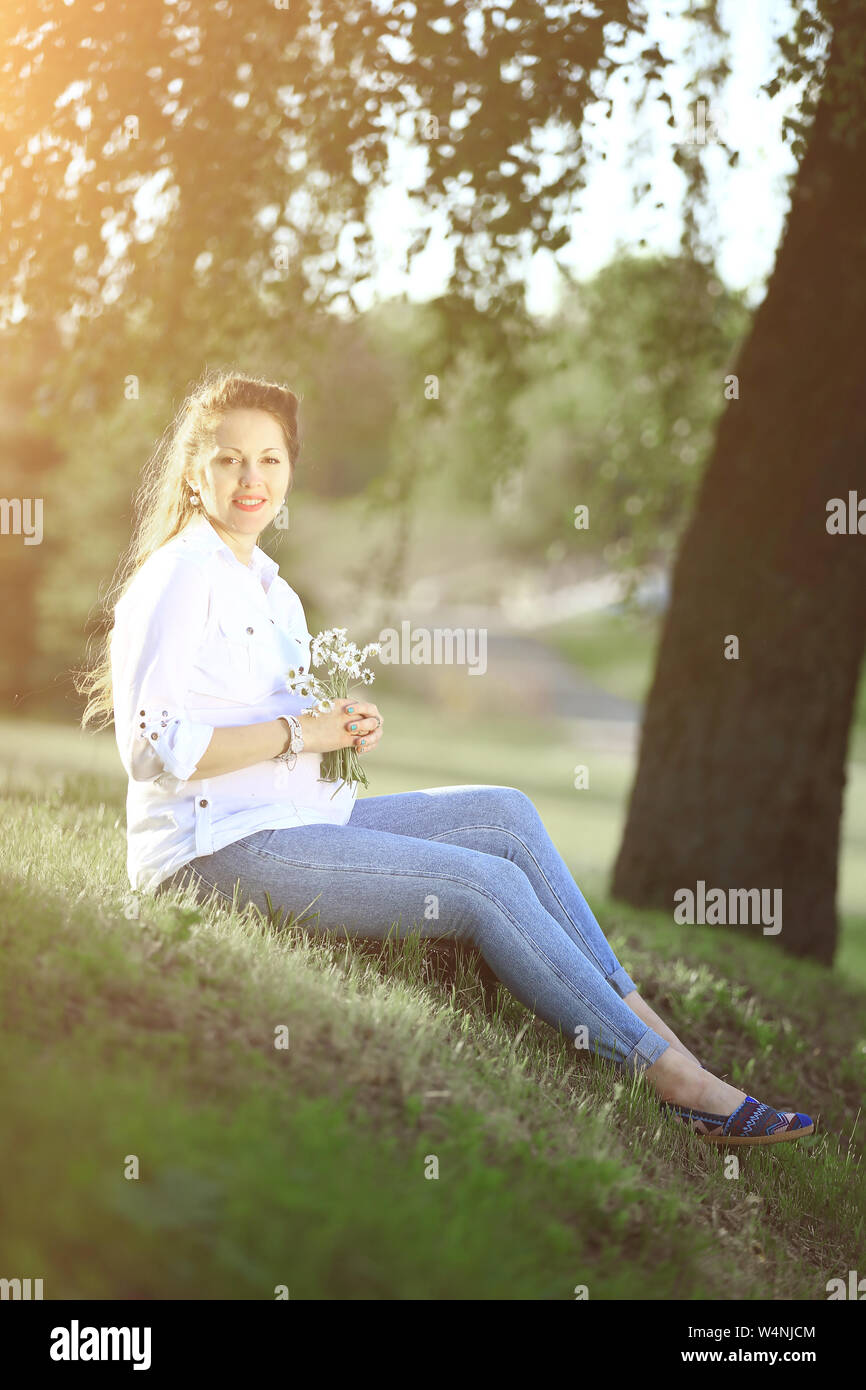 pregnant woman sitting on the grass in a Park on a Sunny day Stock Photo