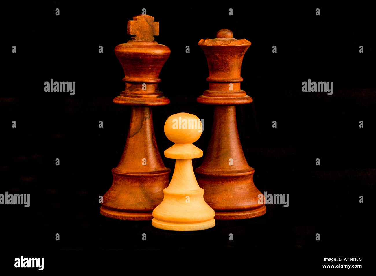 Black King and Queen with white pawn family as interracial adoption concept. Standard chess wooden pieces on black background Stock Photo