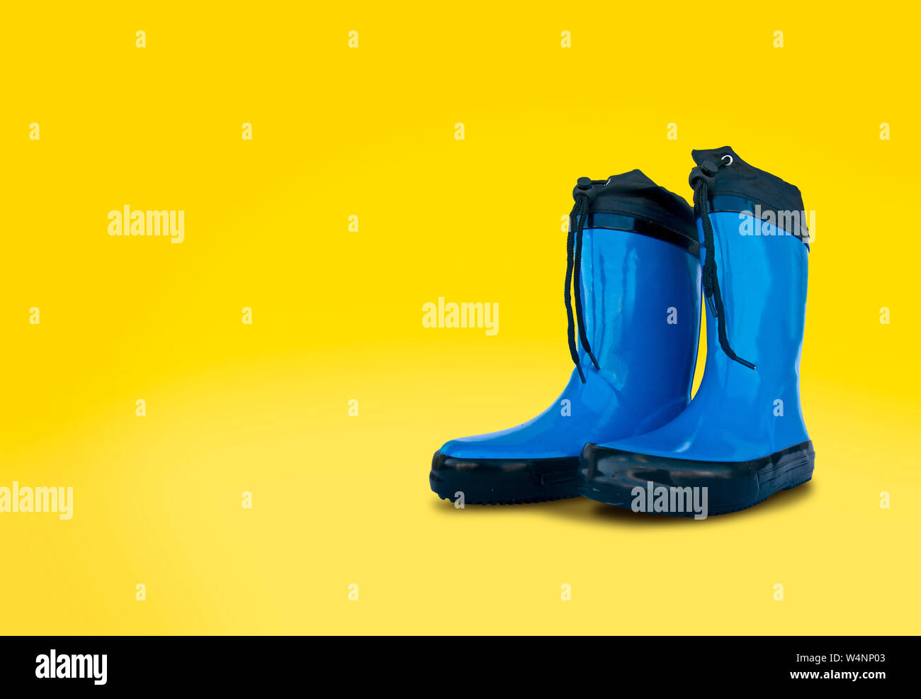 Blue rubber boots isolated on yellow background Stock Photo - Alamy