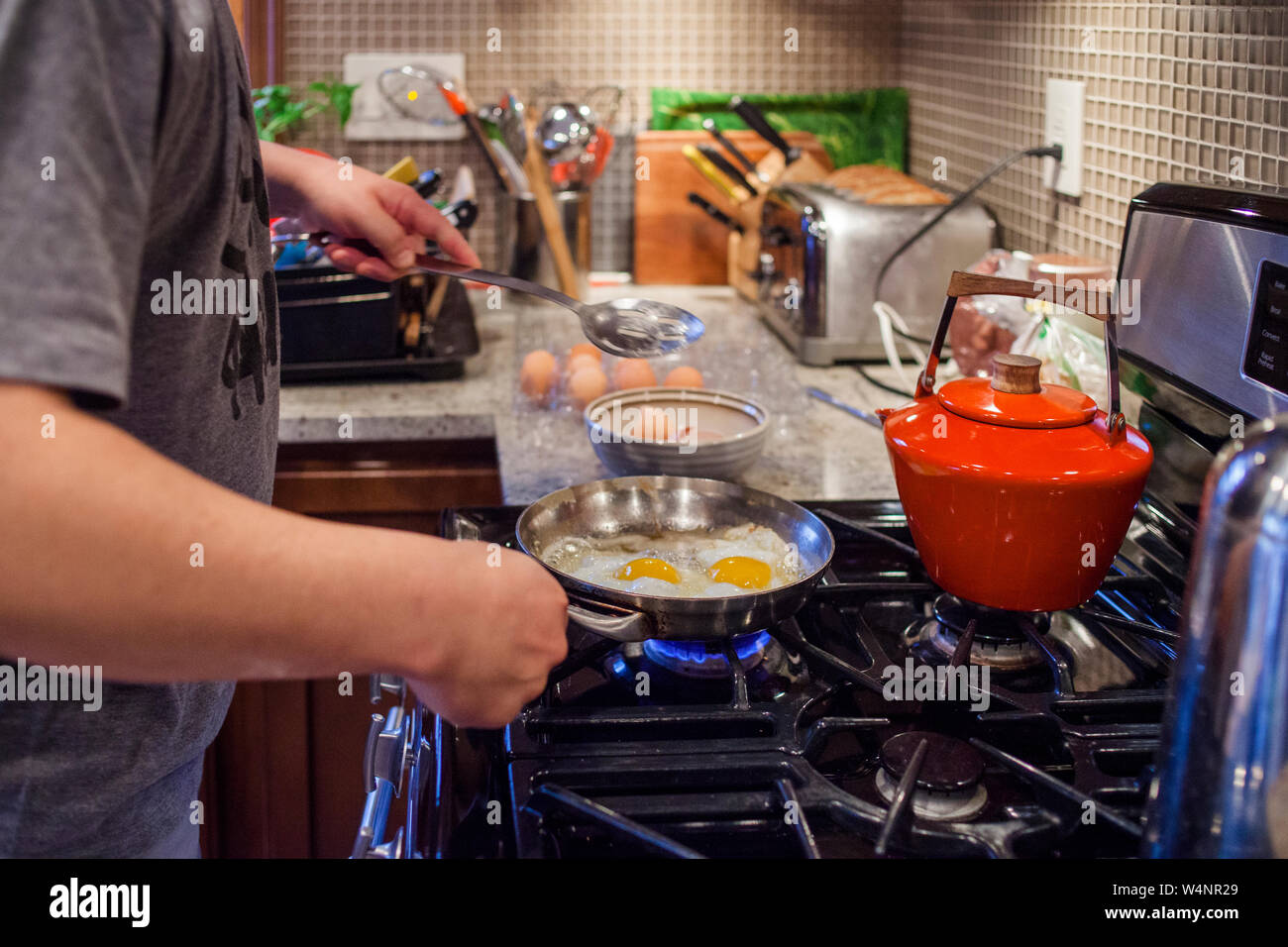 close-up view of a man's hands cooking breakfast at the kitchen stove Stock Photo