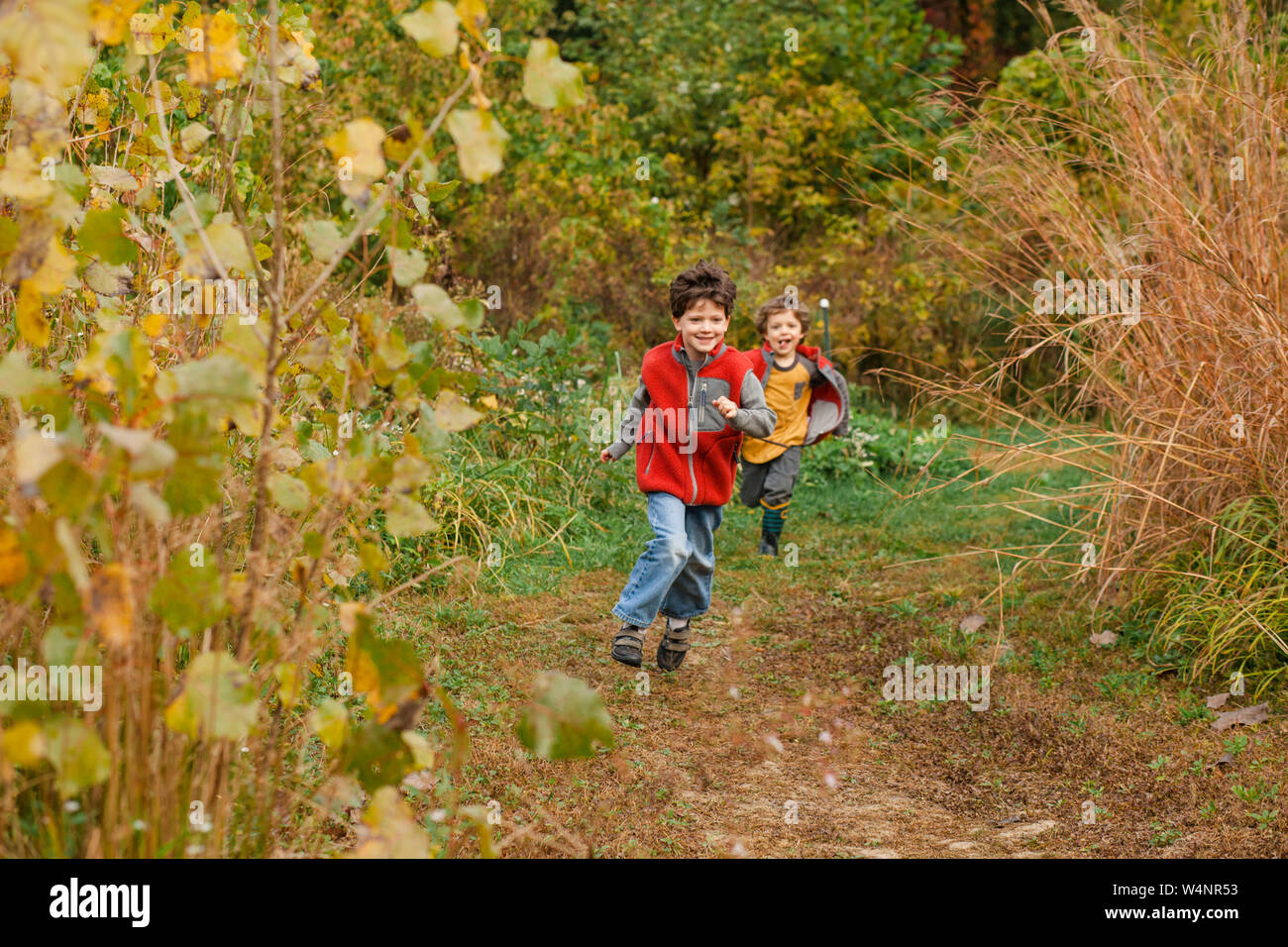 two happy children chase each other through a golden prairie Stock Photo