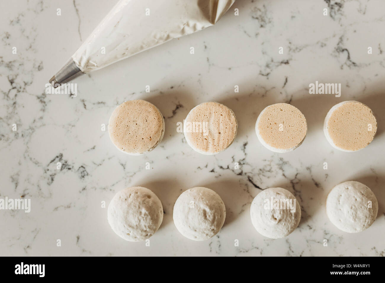 Macaron cookie shells arranged with piping bag full of buttercream Stock Photo