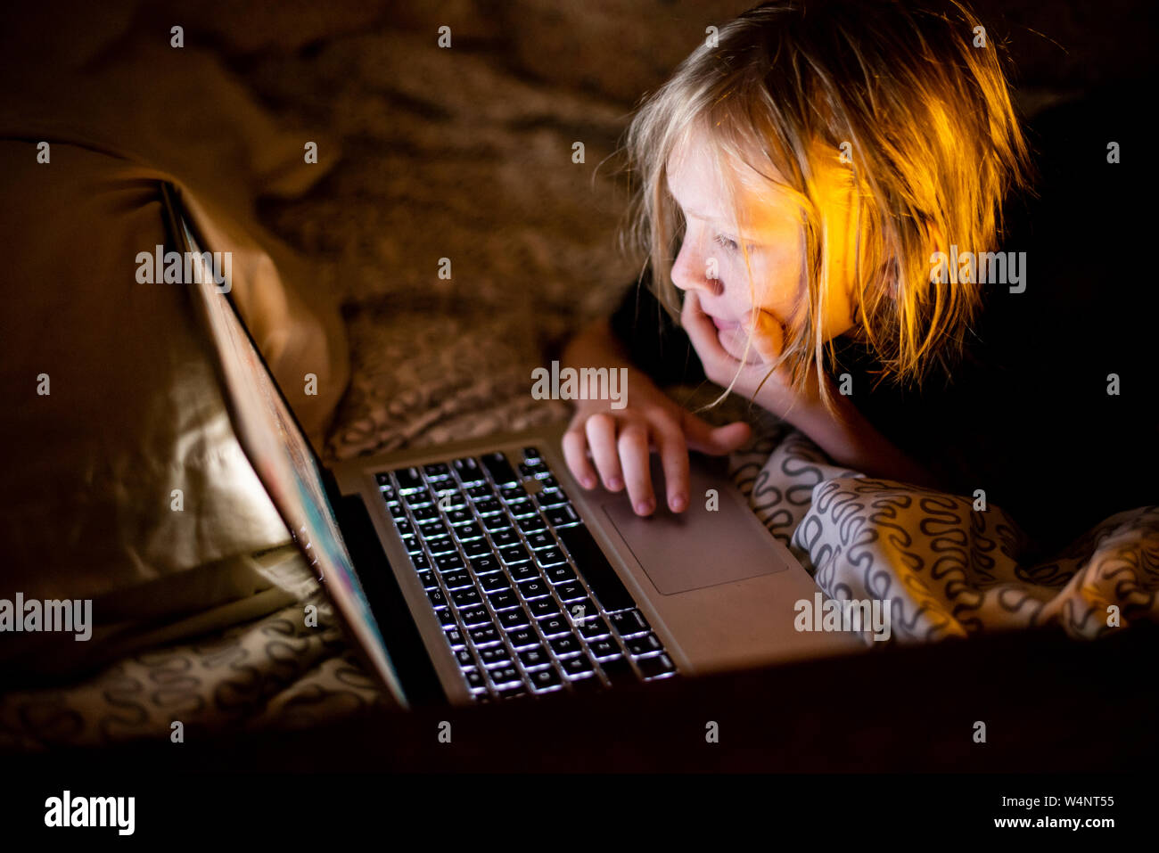 Kid using laptop computer in bed Stock Photo