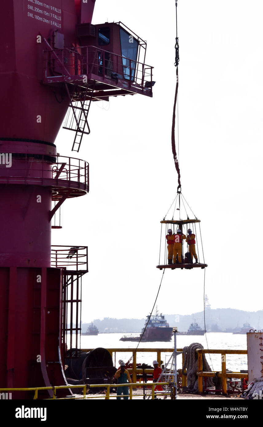 offshore personal transfer using safety basket operate by crane operator Stock Photo
